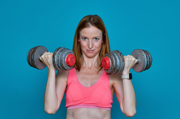 Woman doing physical exercises with very heavy dumbbells