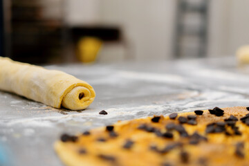 The kitchen in the bakery - the process of making cinnabons, a woman baker uses chocolate in...