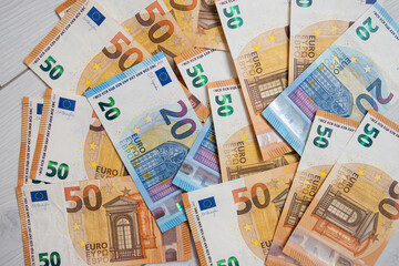 Euro money banknotes. Bundle of 50 and 20 euro bills on white wooden background. Flat lay of euros banknotes