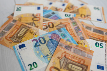 Euro money banknotes. Bundle of 50 and 20 euro bills on white wooden background. Flat lay of euros...
