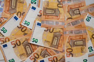 Obraz premium Euro money banknotes. Bundle of 50 euro bills on white wooden background. Flat lay of euros banknotes