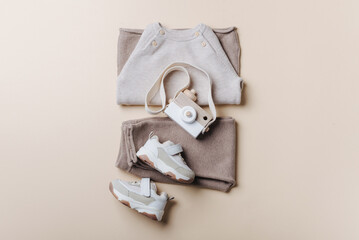Baby stuff and accessories. Set of knitted clothes - sweater, pants, shoes, wooden camera toy. Baby shower concept. Flat lay, top view. Copy space. Fashion children's clothing, shoes