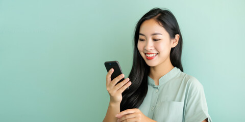 Naklejka premium Jeune femme brune asiatique en train de consulter son smartphone, image avec espace pour du texte, fond neutre vert pâle - Générer par IA