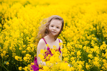 Girl in a pink dress in a field with yellow flowers