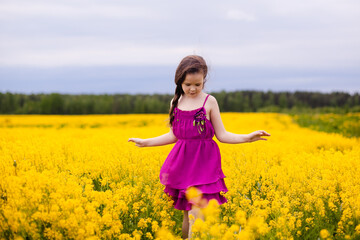 Girl in a pink dress in a field with yellow flowers