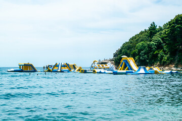People on Inflatable entertainment water attractions and slides on sea. Morgen beach, Montenegro.