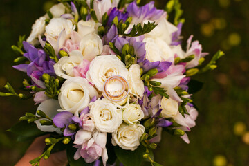 Obraz na płótnie Canvas Wedding bouquet rings with purple and white flowers and buds on green grass.
