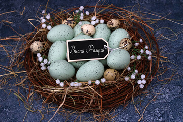 Uova di Pasqua verdi pastello e uova di quaglia in un nido con la scritta Buona Pasqua su un'etichetta. - obrazy, fototapety, plakaty