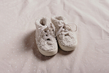 Gender neutral baby teddy shoes and accessories over beige background. Top view, copy space