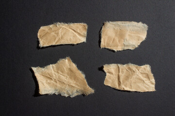 Set of wrinkled brown paper pieces on a black background. Ripped paper.
