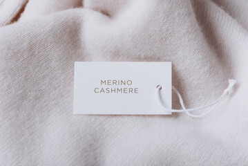 Stack of cashmere clothes with label, tag on beige background. Merino wool clothes. Set of wool...