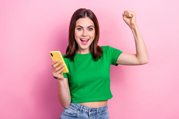 Photo of delighted pretty lady hold telephone raise fist success like subscribe isolated on pink color background