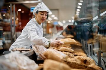 Female baker arranging pastry in supermarket.