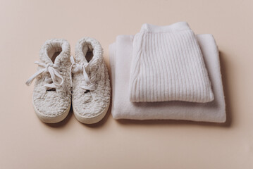 Baby boy knitted clothes, sweater, pants, shoes on beige background. Knitwear. Merino wool, cashmere concept