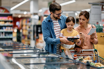 Parents with small daughter buying groceries in supermarket.