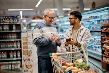 Young man and his senior father buying groceries at supermarket.