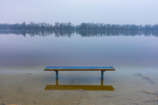 Spring flood on the river. The water level rose and flooded the bench on the shore © Vlad Kazhan