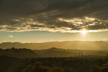 Beautiful view of dry grass on hills with white clouds in a sky during sunrise