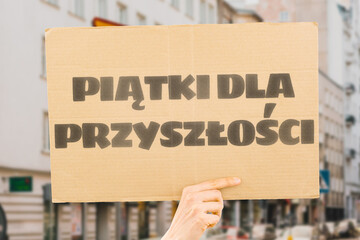 The phrase " Friday For Future " is drawn on a carton banner in a woman's hand. Infection. Destruction. Damage. Bad. Poison. Toxin. Poisoning. Harm. Air. Contamination. Emission. Quality. Zone