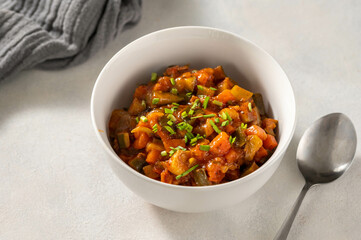 Roasted vegetables stew, vegan food in white bowl.