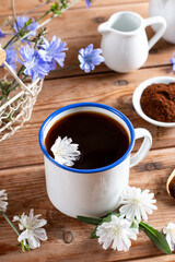 Chicory drink in a white mug with chicory flowers next to it on a board