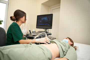 Close up view of ultrasound probe. A young female ultrasound doctor  scanning. Preparing for an...