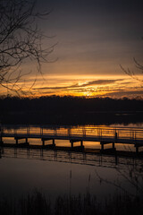 Orange sunset on the lake with the bridge and phragmites silhouettes