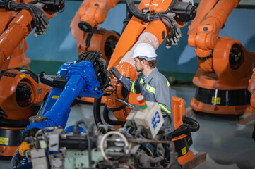 male automation engineer in uniform helmet safety inspection check control heavy machine robot arm system in industrial factory. technician worker check for repair factory machine