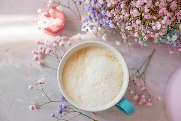 colored macaroon sweets, delicate colored flowers and coffee with milk.
