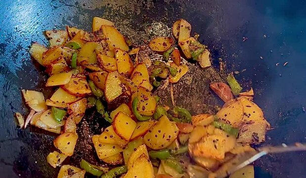 Stir frying potatoes and jalapenos in wok