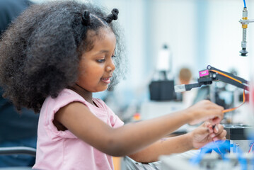Kid female teen child enjoy Machine Learning Robot arm is Moving Under Control robot at technology...