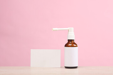 Throat spray bottle with blank label and business card for design template on pink background