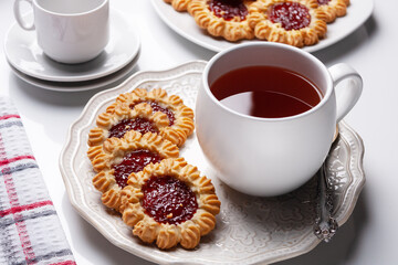 cookies with raspberry jam and a cup of tea on a checkered napkin on the table