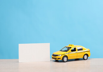 Miniature taxi car with a white business card on table, blue background