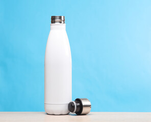 White thermos bottle on the table, blue background