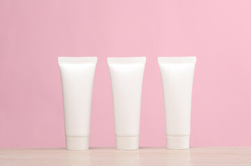 White cream tubes on the table, pink background. Creative layout. Template for design. Beauty mockup