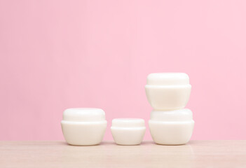 White cream jars on the table, pink background. Creative layout. Template for design. Beauty mockup