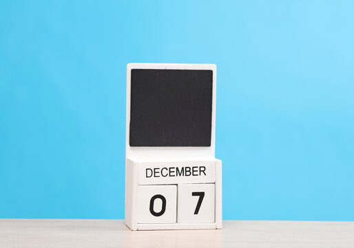 White wooden block monthly calendar with the date december 7 on the table, blue background. Planning, deadline