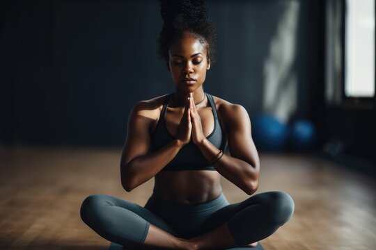A black woman in a yoga class sits in a meditative pose, finding peace and tranquility in her surroundings. Generative AI