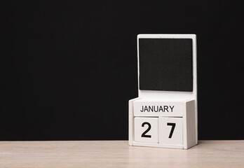 White wooden block monthly calendar with the date january 27 on the table, black blackbackground. Planning