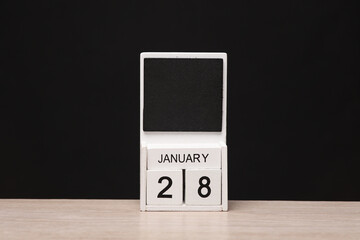 White wooden block monthly calendar with the date january 28 on the table, black blackbackground. Planning