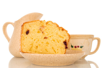 One piece of aromatic homemade raisin cake on saucer with ceramic cup and milk jug, macro isolated on white background.