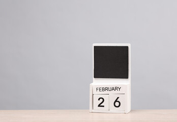 White wooden block monthly calendar with the date february 26 on the table, gray background. Planning, business concept