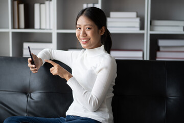 Teenager using mobile smart phone at home while sitting on the sofa.