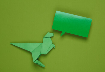 Origami dinosaur with empty speech bubble on green background