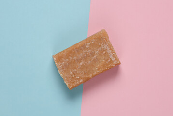 Bar of laundry soap on a blue-pink pastel background. Top view