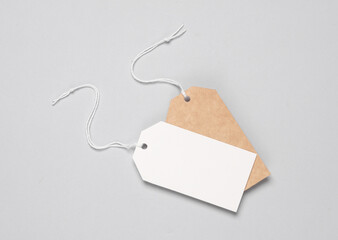 Empty brown craft and white paper price tags with string on gray background. Template for design