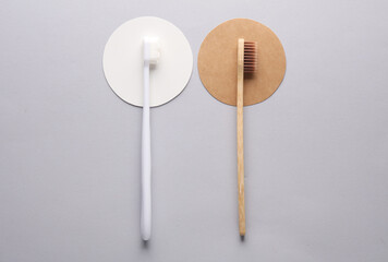 Plastic and wooden toothbrushes on gray background with circles. Eco concept. Top view.