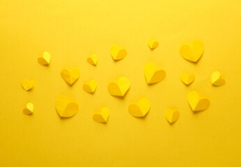 Paper-cut yellow hearts on a yellow background. Love, romantic concept. Creative layout. Top view
