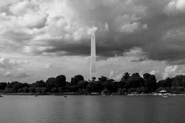 Scenic grayscale view of the Washington Monument against a stormy cloudy sky across the water